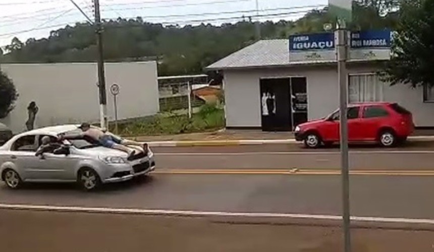 Assaltantes de banco levam refém no capô de carro durante a fuga
